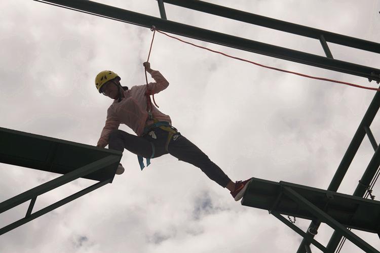 学员们互相协助,各自完成了高空断桥的挑战.