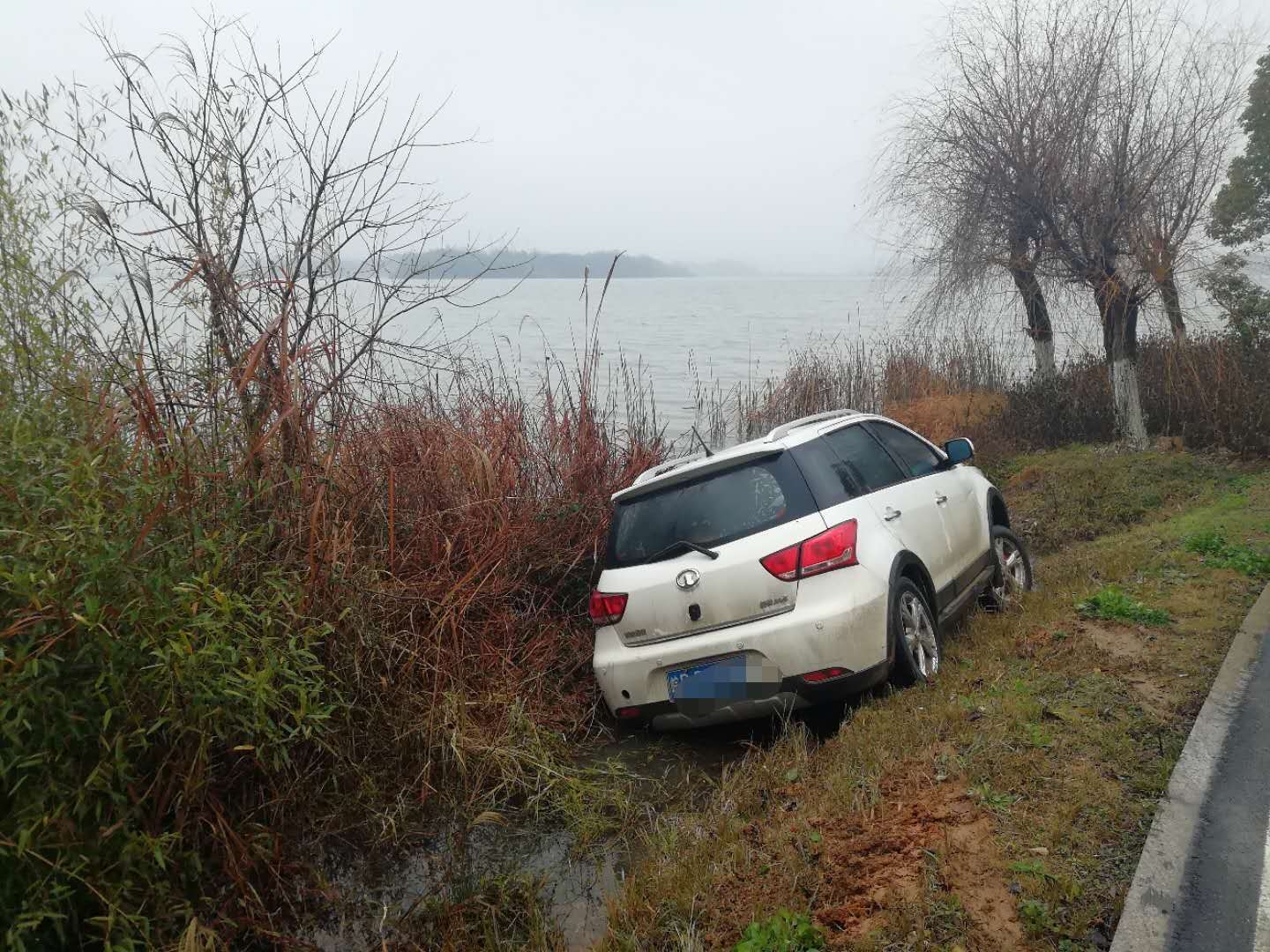 今晨一辆白色小轿车操作不当,掉进平天湖旁的排水沟.