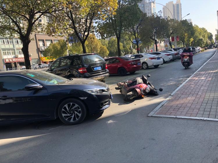 三中附近发生一起交通事故,一辆黑色轿车撞倒电瓶车